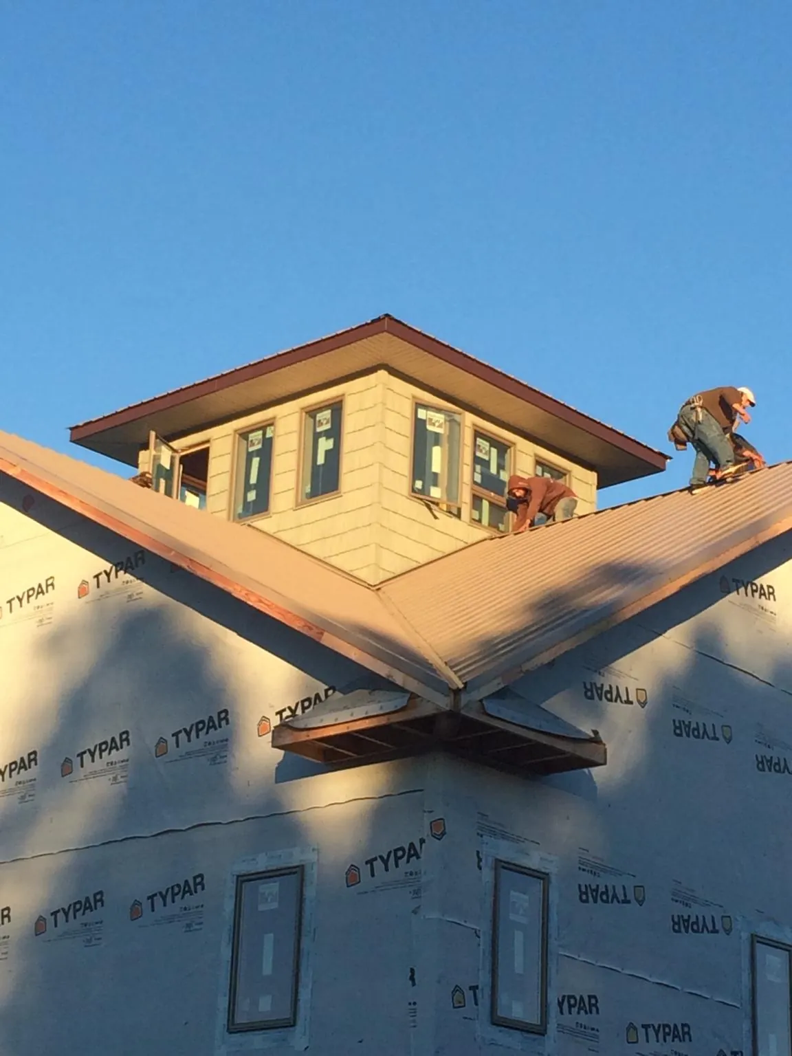 Roofers working around a rooftop cupola on a new metal roof at sunset — Roof Waterproofing in Dumont by Roofing Brothers